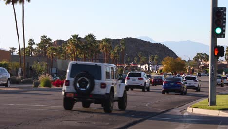 La-Quinta-resort,-California,-cars-drive-along-sunny-boulevard-palm-tree-lined