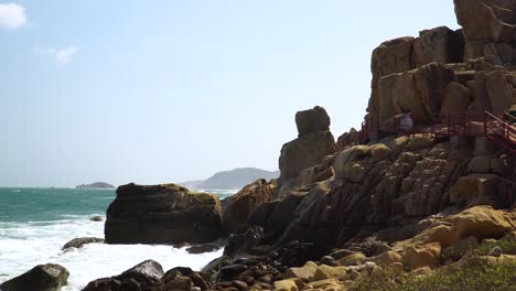 Tourists-walk-on-viewing-platform-on-rocks-above-turquoise-sea-waves