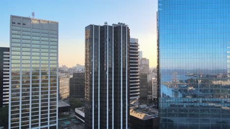 Aerial-dolly-right-of-Puerto-Madero-neighborhood-reflected-on-window-glass-skyscrapers-at-sunset,-Buenos-Aires