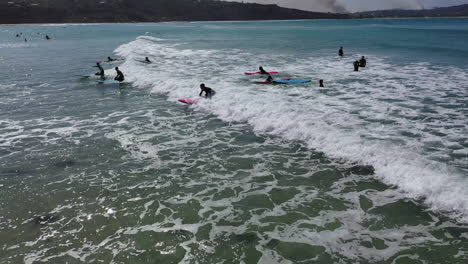 Aerial:-Instructors-launch-kids-onto-small-green-waves-in-surf-class
