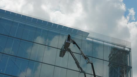 Arbeiter-Auf-Einer-Erhöhten-Kranplattform-Reinigen-Die-Glasfassade-Eines-Modernen-Gebäudes-In-Paris,-Frankreich