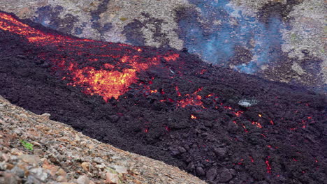 Hombre-Adulto-Caminando-Sobre-Rocas-Cerca-Del-Río-De-Lava-Después-De-La-Erupción-En-Islandia