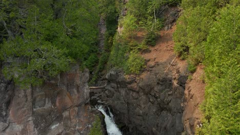 aerial-view-of-River-with-a-waterfall-in-the-middle-of-a-canyon-in-Northern-Minnesota-during-summer-months,-Caribou-falls