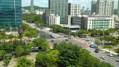 Kreuzung-Der-Hauptstraßen-Der-Stadt-Daejeon-Mit-Verkehr,-Der-An-Hochhäusern-Und-Wolkenkratzern-Vorbeifährt,-Polizeistationsgebäude-Tagsüber-In-Südkorea