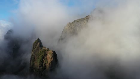 Drone-shot-moving-backwards-in-the-sunny-and-foggy-landscape-above-Pico-das-Torres-in-Madeira