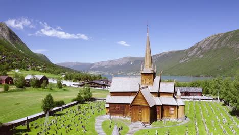 Exterior-Frontal-De-La-Iglesia-Lom-Stave-Con-Vistas-A-La-Montaña-Y-Al-Río-Otta-Durante-El-Día-En-Noruega