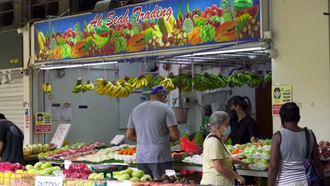 Vendedor-Y-Clientes-En-El-Puesto-De-Frutas-En-El-Mercado-De-Singapur