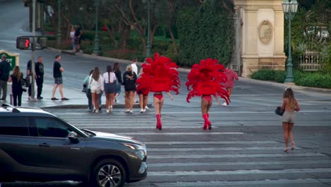 Dos-Bailarinas-Con-Deslumbrantes-Trajes-Rojos-Cruzan-La-Calle-En-La-Franja-Principal-De-Las-Vegas