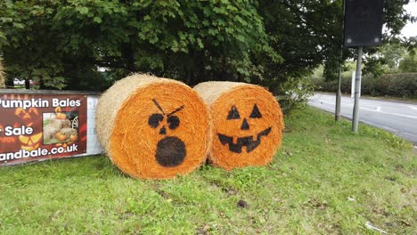 Spooky-rolled-hay-bale-painted-Halloween-holiday-pumpkin-funny-faces-farmland-decoration