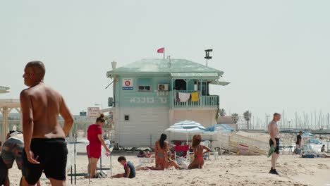 Playa-En-Israel,-Ashkelon,-Salvavidas-Sukkah-Con-Vitrina-Giratoria-De-Aire-Acondicionado-Y-Gente-Alrededor-Pasando-El-Rato-En-La-Playa