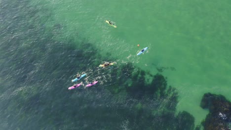 Surfer-shool-batch-cruising-at-turquoise-waters-of-Marazion-UK-aerial