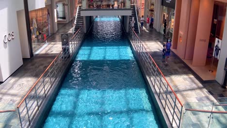 Künstlicher-Fluss-Mit-Sauberem,-Blauem-Wasser,-Der-Durch-Das-Einkaufszentrum-Shoppes-In-Singapur-Fließt