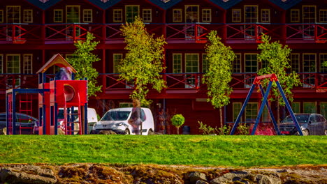 View-of-a-playground-for-kids-with-kids-busy,-excited-and-joyful-children-having-fun-and-playing-on-swing,-slide,-playhouse-and-swing-and-running-around-in-timelapse-from-noon-to-evening