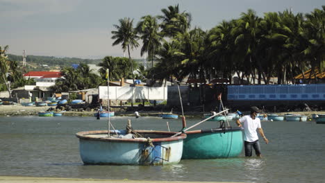 Mann-Steht-Neben-Zwei-Traditionellen-Vietnamesischen-Runden-Fischerbooten,-Die-Am-Hafen-Schwimmen
