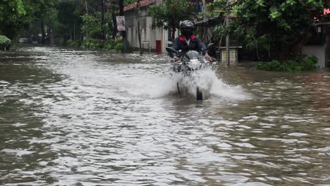 Menschen,-Die-Während-Starker-Regenfälle-In-Kalkutta-Mit-Dem-Motorrad-In-Einer-überschwemmten-Straße-Fahren