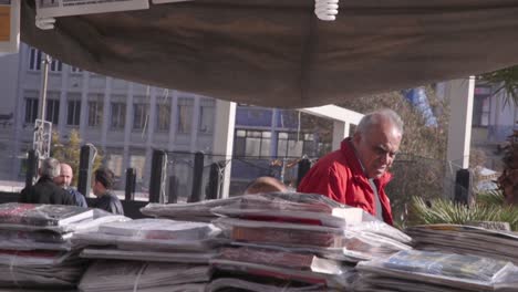 Man-walking-by-a-newspaper-stand-in-the-center-of-Athens,-Greece