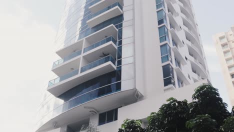Una-Inclinación-Vertical-Empinada-Del-Frente-De-Un-Condominio-Residencial-De-Lujo,-La-Fachada-De-Vidrio-Azul-Brinda-A-Los-Propietarios-La-Vista-Aérea-Más-Espectacular-De-La-Ciudad,-Ciudad-De-Panamá