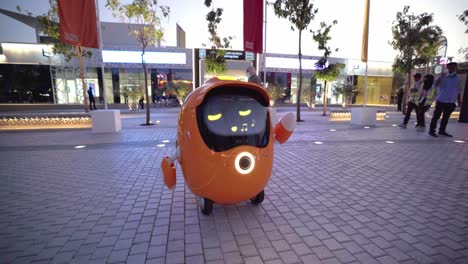 EXPO-2020,-Dubai,-05-February-2022---EXPO-Robot-Orange-Opti-Assisting-A-Guest-Helping-And-Singing