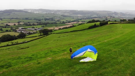 Parallax-view-of-a-paraglider-inflating-his-wing-before-take-off-with-beautiful-English-countryside-as-a-backdrop