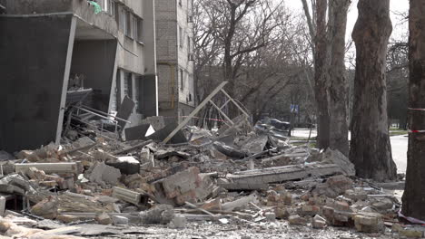 A-car-and-a-man-on-a-bicycle-pass-a-hotel-that-was-hit-by-a-cruise-missile,-destroying-a-large-section-of-the-building-during-the-Russian-invasion-of-Ukraine