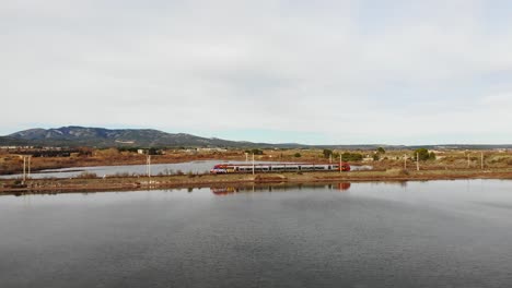 Aerial:-passenger-train-on-a-dam-by-the-sea-in-southern-France-during-winter