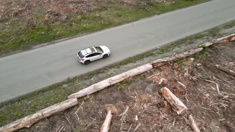 Above-a-Subaru-Crosstrek-traveling-across-a-clear-cut-forest-area,-aerial-spin-and-track-back,-Illustrative-Editorial