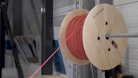 Man-pulling-electric-red-wire-from-a-spool-used-for-solar-panel-installation-by-hand,-Close-up-shot