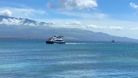 Tour-boat-full-of-passengers-cruising-along-the-clear-blue-waters-of-Maalaea-Bay,-Maui,-Hawaii-island
