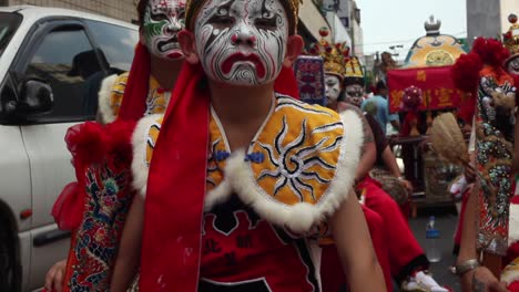 Niño-Sentado-Con-Pintura-Facial-Del-Demonio-Guerrero-Chino-Durante-El-Desfile-Del-Festival-Tradicional-Del-Templo