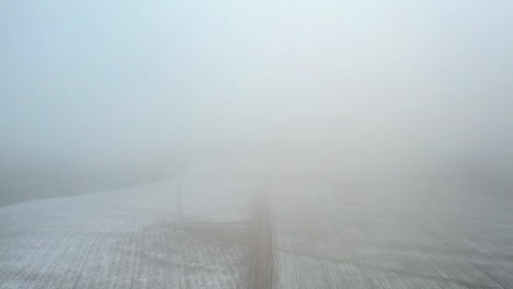 Neblige-Szene-Einer-Windmühlenfarm-Auf-Einem-Wolkenverhangenen-Berghang---Luftaufnahme