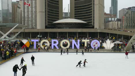 People-ice-skate-next-to-anti-war-rally-with-Ukrainian-flags,-Toronto