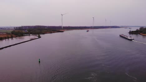 Aerial-View-Of-Martie-Cargo-Ship-Approaching-In-Distance-With-Still-Wind-Turbines-In-Background-On-Overcast-Day