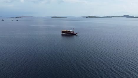 Luftaufnahme-Eines-Schiffes,-Das-An-Einem-Bewölkten-Tag-In-Ruhigen-Gewässern-Vor-Der-Insel-Komodo-Schwimmt