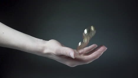 Hand-throwing-and-catching-shiny-Bitcoin-coins,-black-background