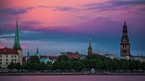 View-of-cathedrals-over-Daugava-river-in-Riga,-time-lapse-of-pink-sky,-sunset