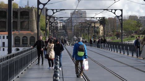 People-walking-across-Dom-Luis-I-Bridge-on-sunny-day,-Porto