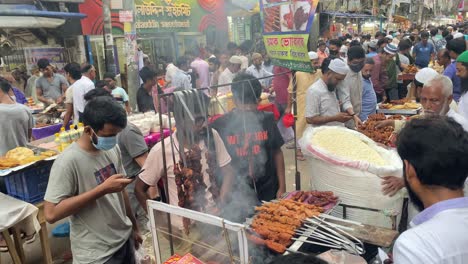 Street-barbeque-cooking-in-local-Old-Dhaka-fast-food-market,-handheld-view