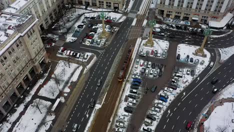 Aerial-view-following-a-tram-on-the-snowy-streets-of-Warsaw,-winter-in-Poland