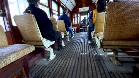 Interior-De-Tranvía-Antiguo-De-Madera-Con-Personas-Sentadas-En-Sillas-Durante-La-Gira-De-Viaje-En-La-Ciudad-De-Oporto---Vista-Trasera