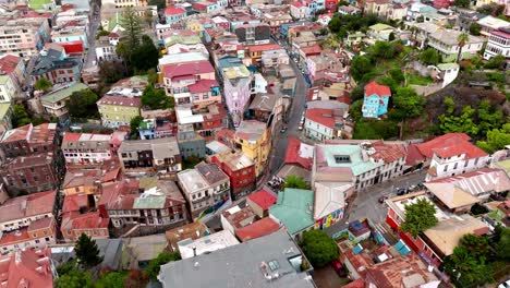 Aerial-dolly-in-of-colorful-neighborhood-houses-in-Alegre-Hill-and-street-that-divides-it-from-Concepcion-Hill,-Valparaíso,-Chile