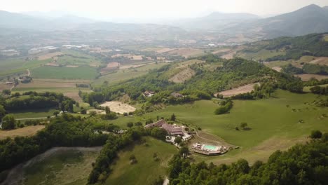 Panning-shot-by-drone-of-some-fields,-forests-and-hills-in-the-italian-countryside