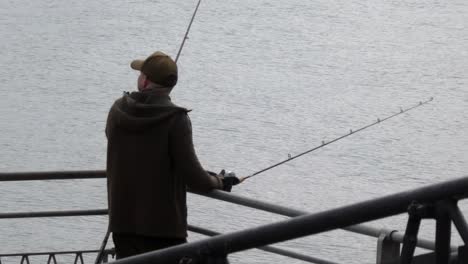 Man-with-fishing-rod-on-Llandudno-pier-jetty-preparing-and-waiting-in-anticipation