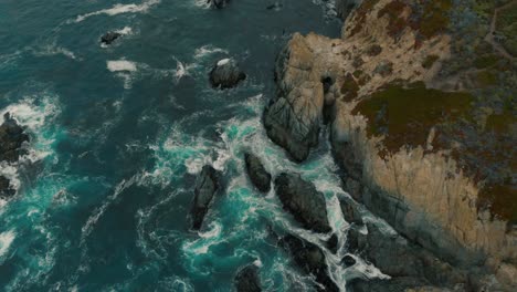 Bird's-eye-view-of-a-rocky-coast,-majestic-waves-crashing-into-the-cliffs