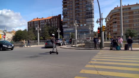 Man-on-electric-kick-scooter-wearing-helmet,-driving-through-traffic