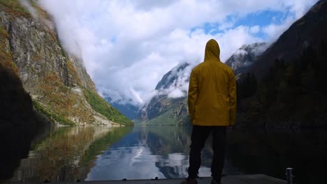 Hombre-Con-Una-Chaqueta-Amarilla-Parado-En-Un-Muelle-Para-Disfrutar-Del-Impresionante-Y-Sognefjord-De-Noruega