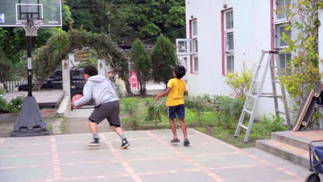 Indisches-Kind-Und-Asiatischer-Erwachsener-Spielen-Eine-Partie-Unbändigen-Basketballs,-Gefilmt-In-Zeitlupe-Mit-Blick-Auf-Das-Spielfeld