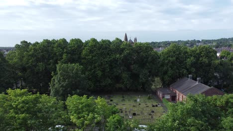 Aerial-view-rising-above-tall-trees-to-reveal-church-spire-and-rural-countryside-village-houses