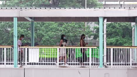 Eine-Stationäre-Zeitlupenaufnahme-Von-Menschen,-Die-Bei-Starkem-Regen-über-Die-Mongkok-Fußgängerbrücke-In-Hongkong-Gehen