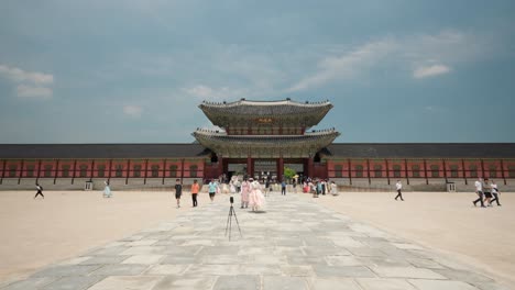 A-Korean-couple-in-hanbok-clothes-takes-a-selfie-photo-in-front-of-Heungnyemun-Gate-when-other-tourists-pass-by---visiting-Gyeongbokgung-Palace