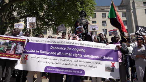 Los-Manifestantes-Sudaneses-Sostienen-Una-Pancarta-Que-Dice:-&quot;denunciar-El-Genocidio-En-Curso-En-Darfur-Y-Todas-Las-Violaciones-De-Los-Derechos-Humanos-En-Sudán&quot;-En-Una-Protesta-En-Whitehall-Oponiéndose-A-La-Guerra-En-Sudán